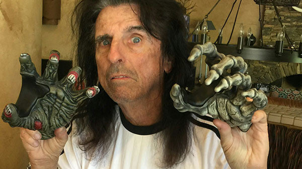 Alice Cooper holding a zombie and a skeleton guitar hangers