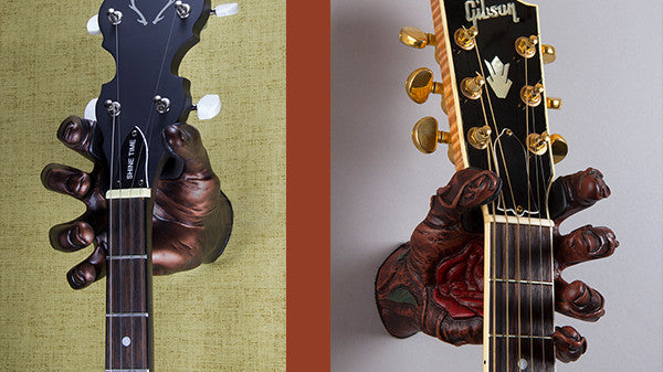 Banjo and Gibson acoustic guitar hanging from hand shaped acoustic guitar hangers