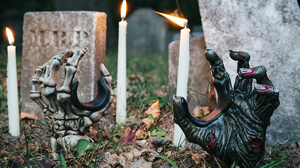 zombie hand and skeleton hand guitar hangers sticking out of the ground in cemetery