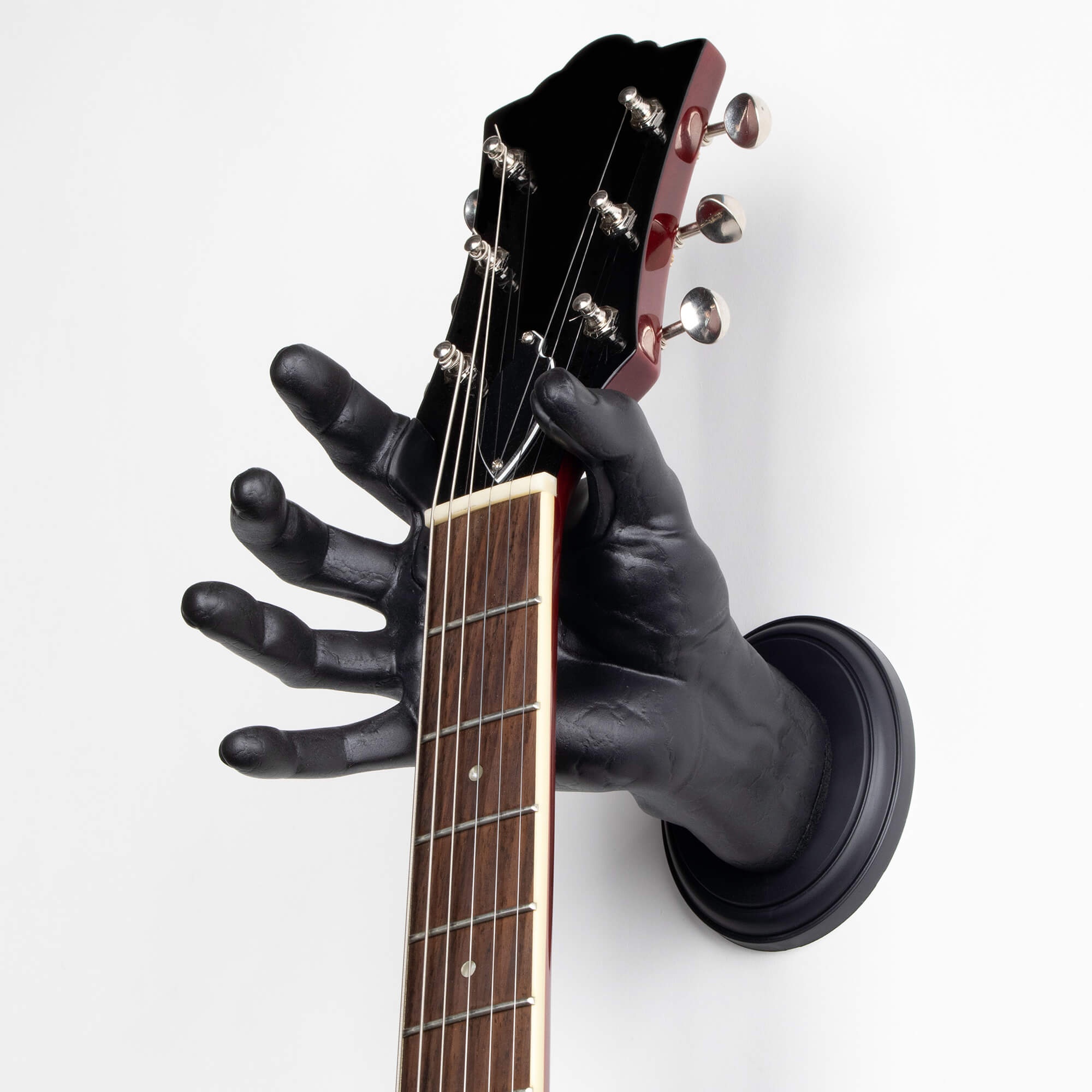 Guitar hanging on the wall with hand shaped guitar hanger.