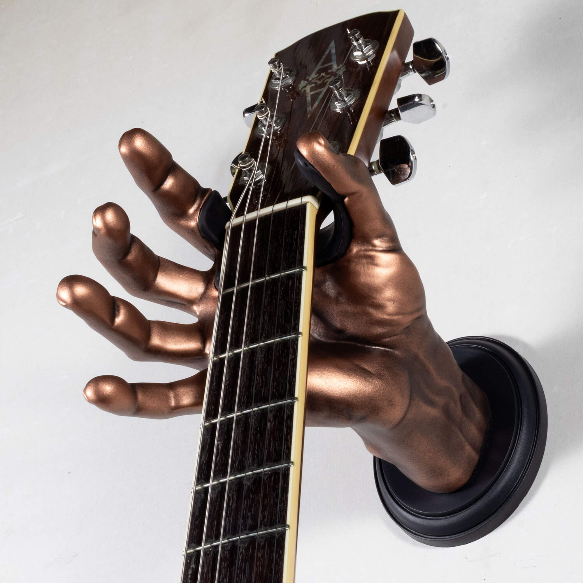 Copper acoustic guitar hanger in the shape of a hand on a white backkground.