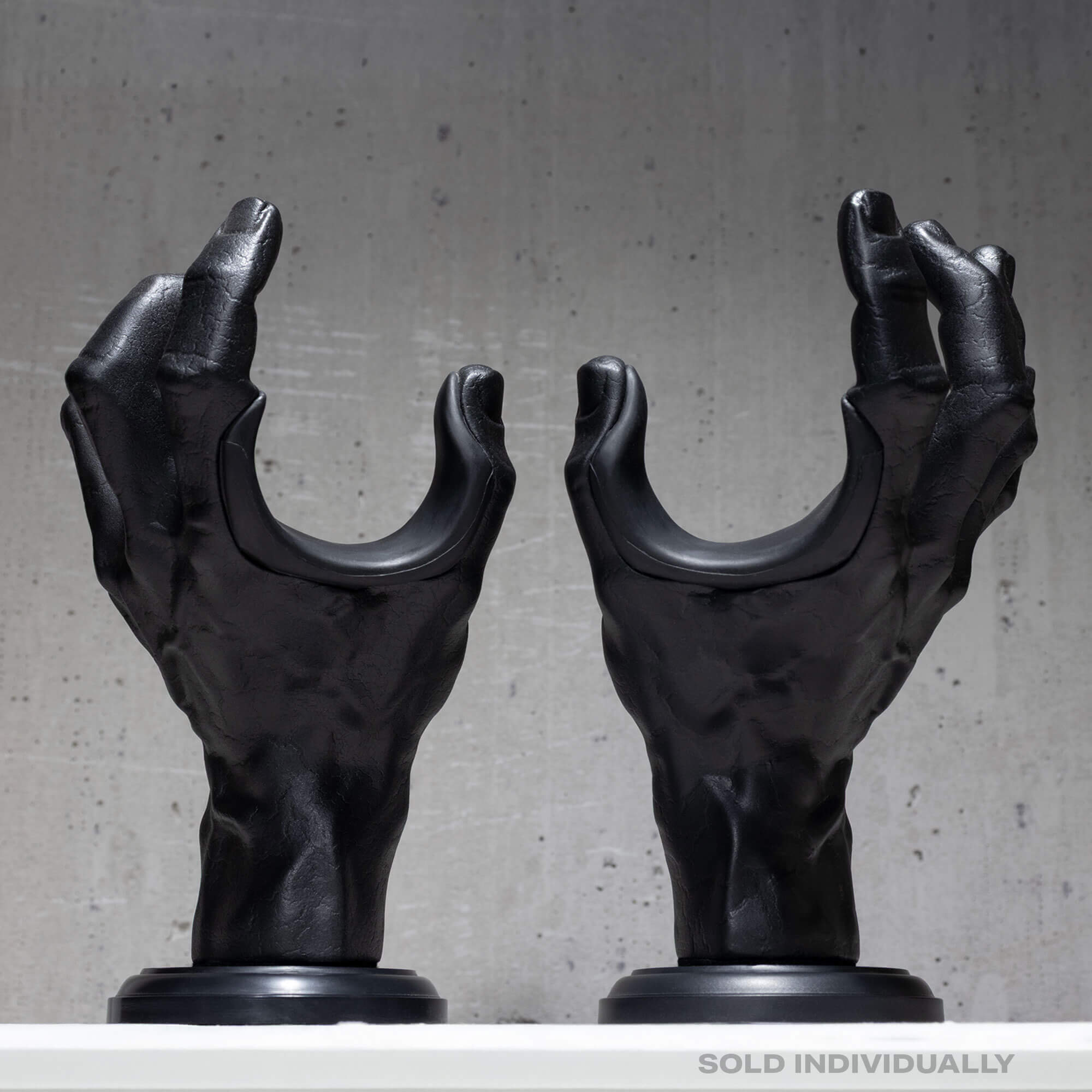 Pair of hand shaped guitar wall holders on grey background.