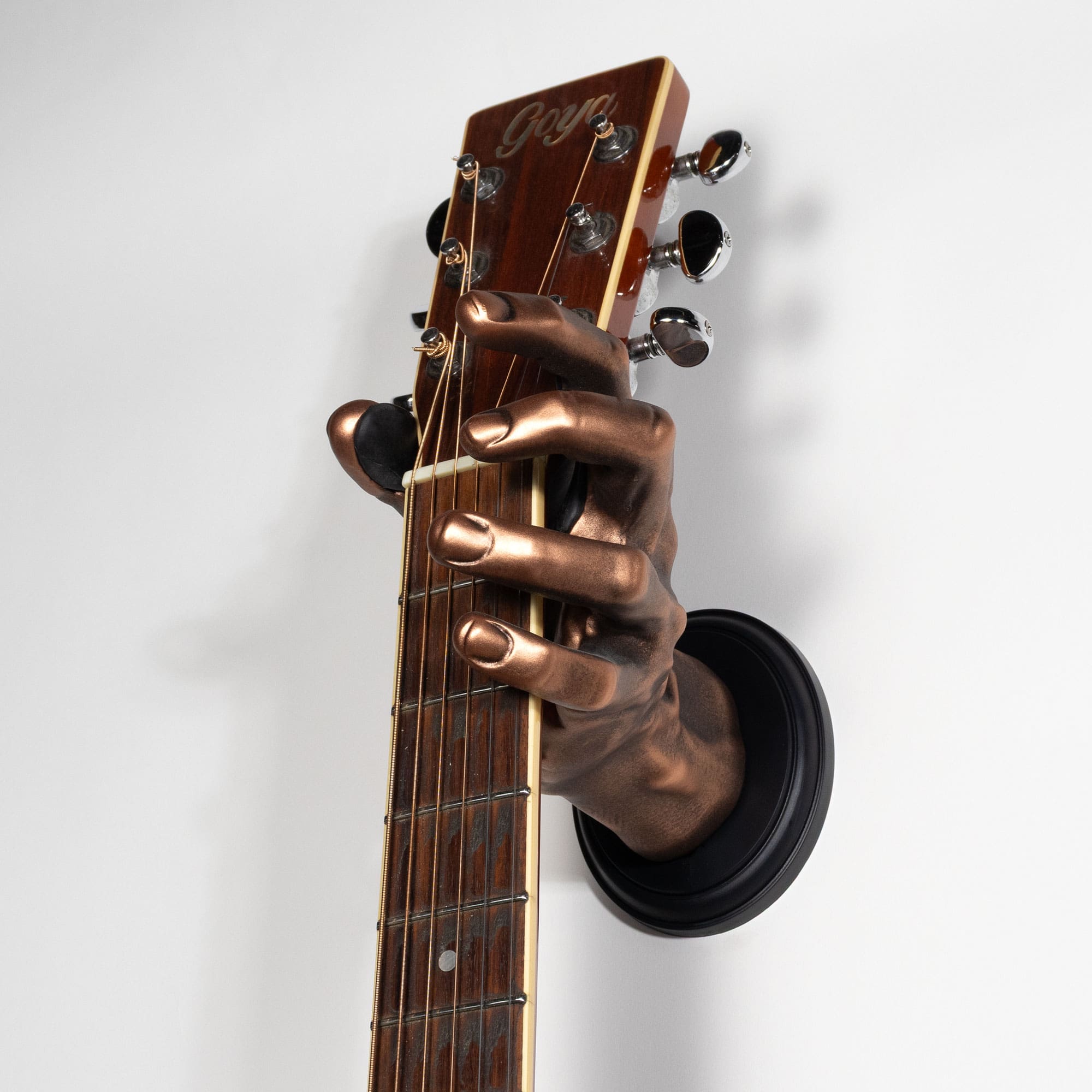 Guitar hanger shaped like a Bronze hand holding a guitar neck against a white background.