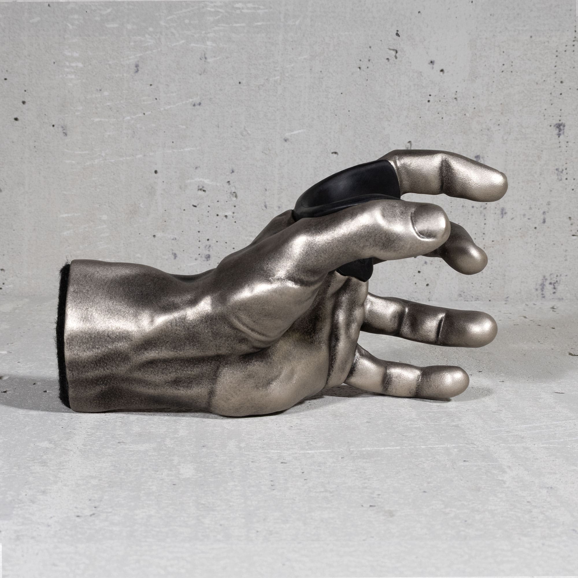 Metallic hand sculpture guitar hanger on a gray concrete surface