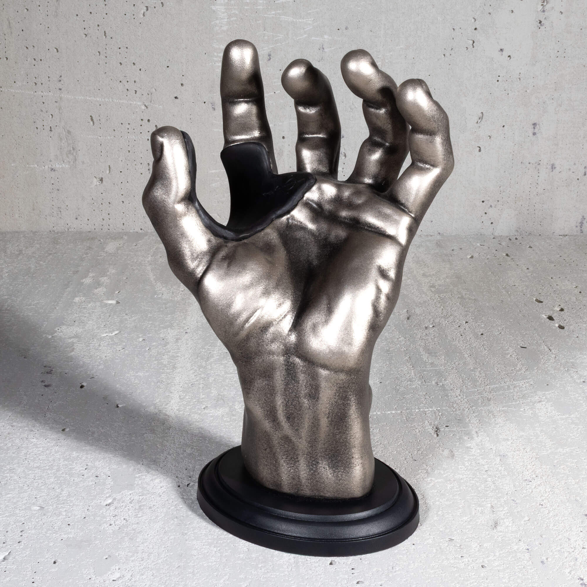 Silver antiqued hand guitar hanger upright view on grey background.