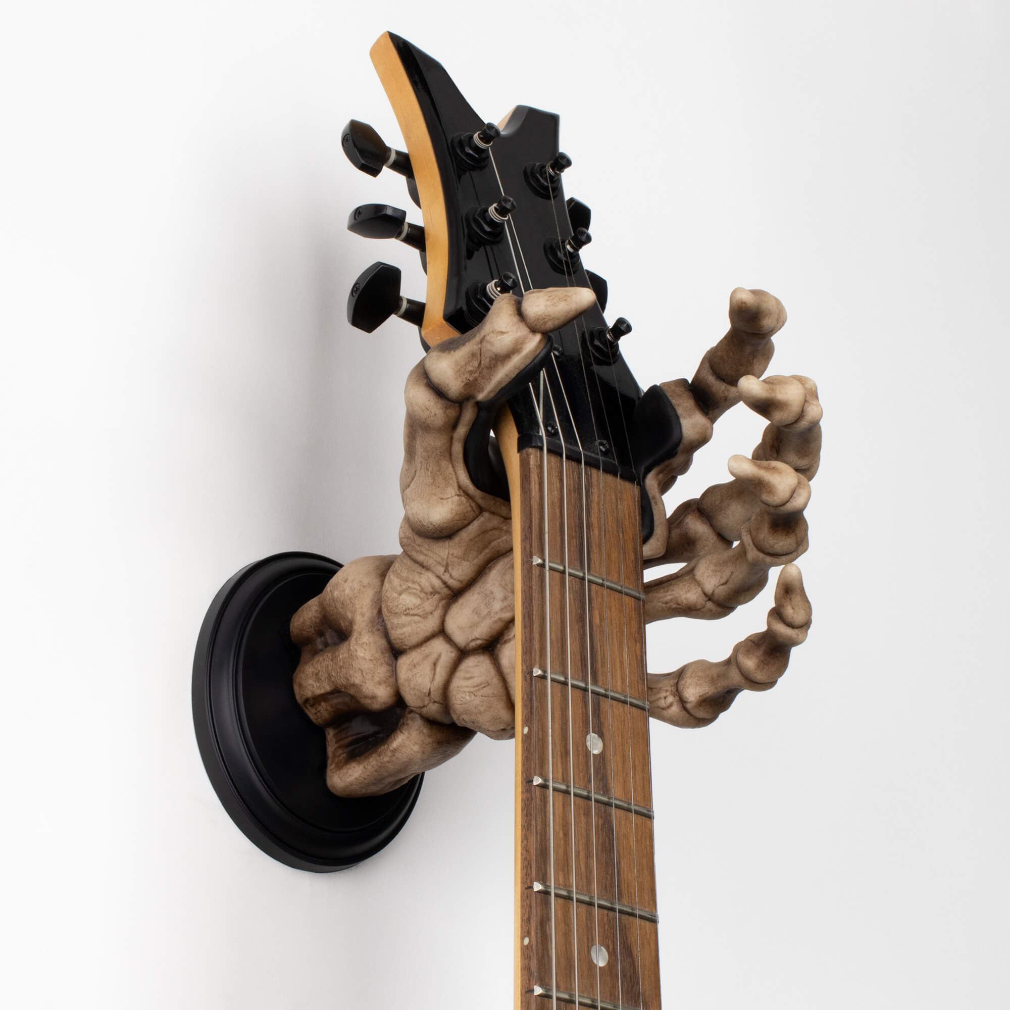 Skeleton hand electric guitar wall mount holding dean guitar on white background.