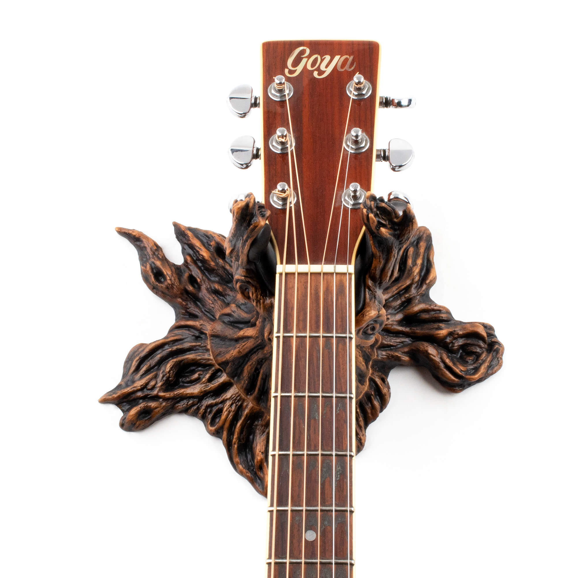Acoustic guitar hanger that looks like a tree branch on white wall.
