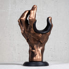 Copper hand guitar wall hanger with black pad on grey background.