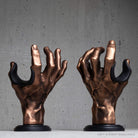 Pair of copper hand guitar hanger wall mounts on grey background.