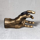 Gold hand sculpture  guitar hanger on a gray surface.