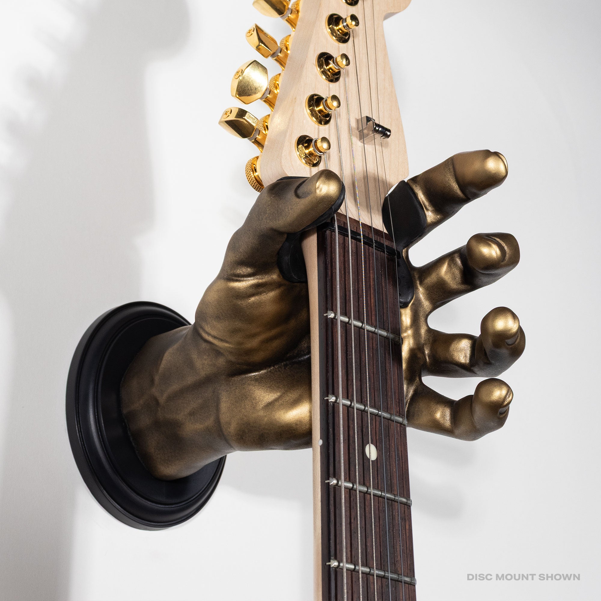 Bronze hand holding a guitar on a gray background.