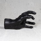 Black crackle finish hand shaped guitar hanger on grey background.