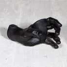 Black cast hand sculpture  instrument hanger on a gray concrete surface.