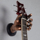Bronze hand shaped guitar hanger wall mount holding a guitar neck against a grey background.
