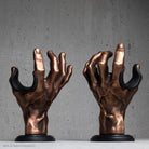 Bronze guitar hanger hand sculptures on a gray background
