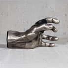Metallic hand sculpture  guitar hanger on a gray concrete surface

