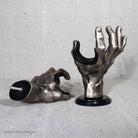 Metallic hand-shaped instrument wall mounts on a concrete surface.

