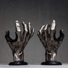 Pair of hand guitar hangers silver on dark grey wall.