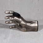 Inside view of antiqued silver hand used to mount instruments, specifically guitars, to the wall. 