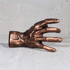 Copper hand wall hanger for guitars on grey background.