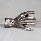 Metallic hand sculpture guitar hanger wall mount. on a gray surface

